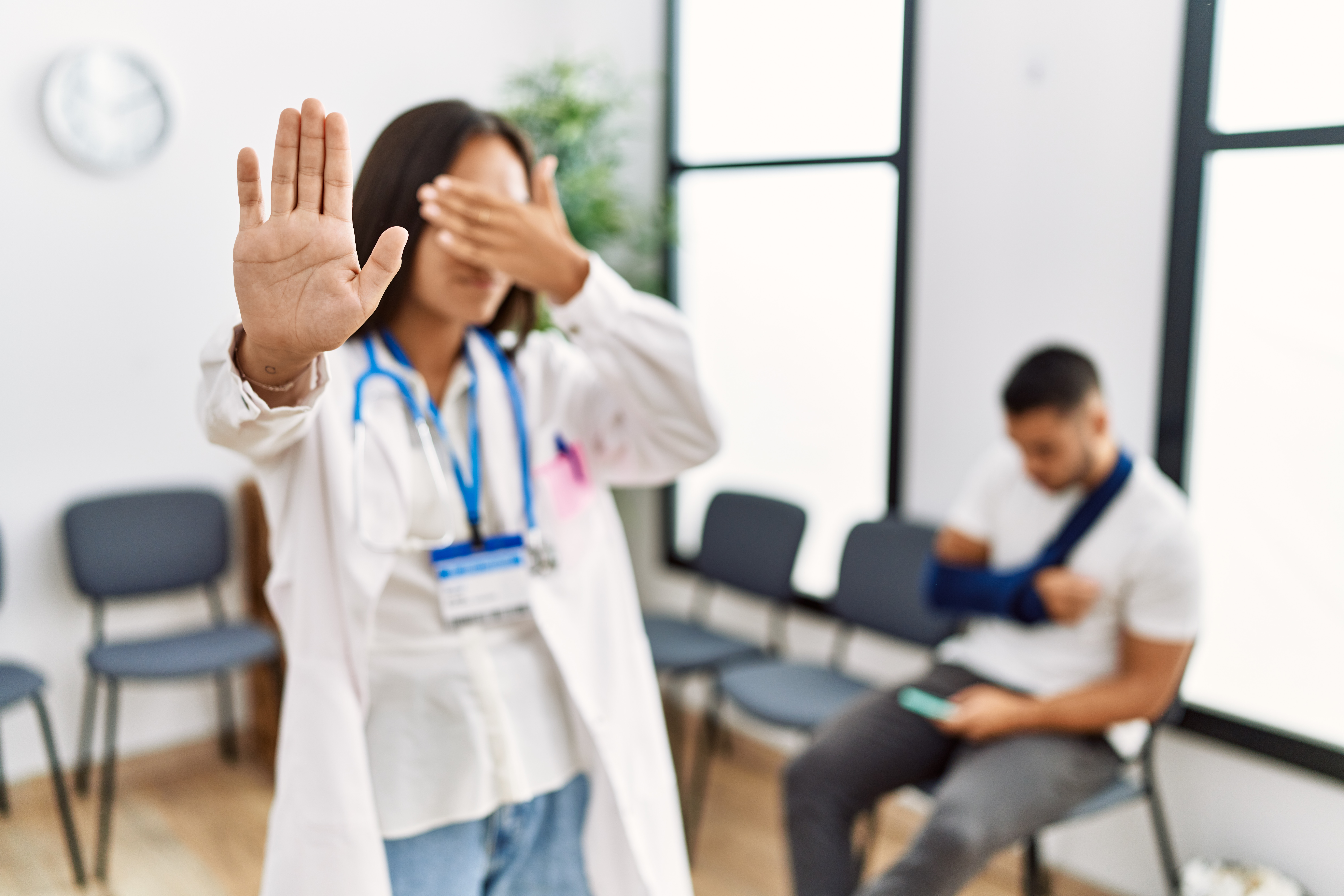 Young asian doctor woman at waiting room with a man with a broken arm covering eyes with hands and doing stop gesture with sad and fear expression. embarrassed and negative concept.